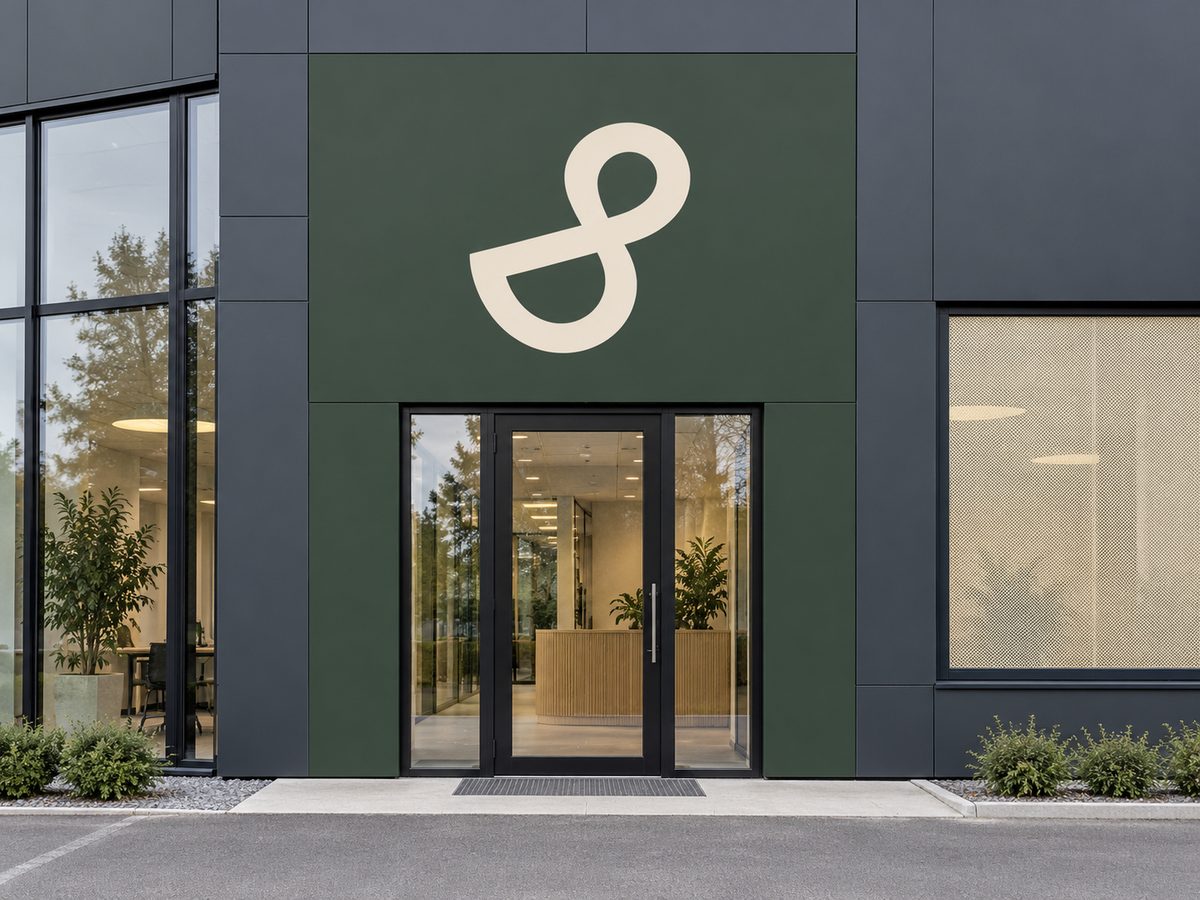 Inngangsparti med grønn folie på fasaden og stor logo over døra